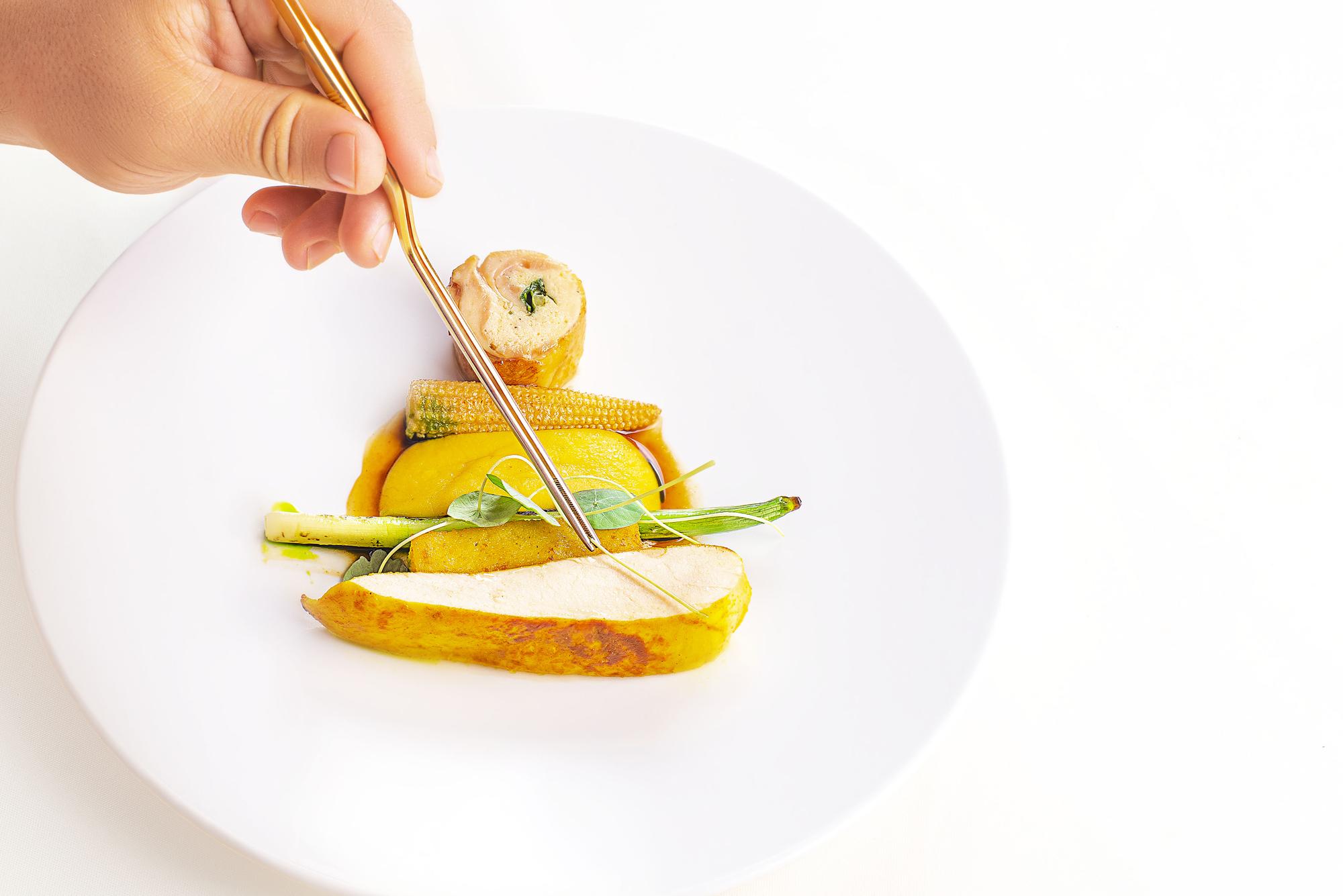Chef plating a colorful dish in a bright kitchen