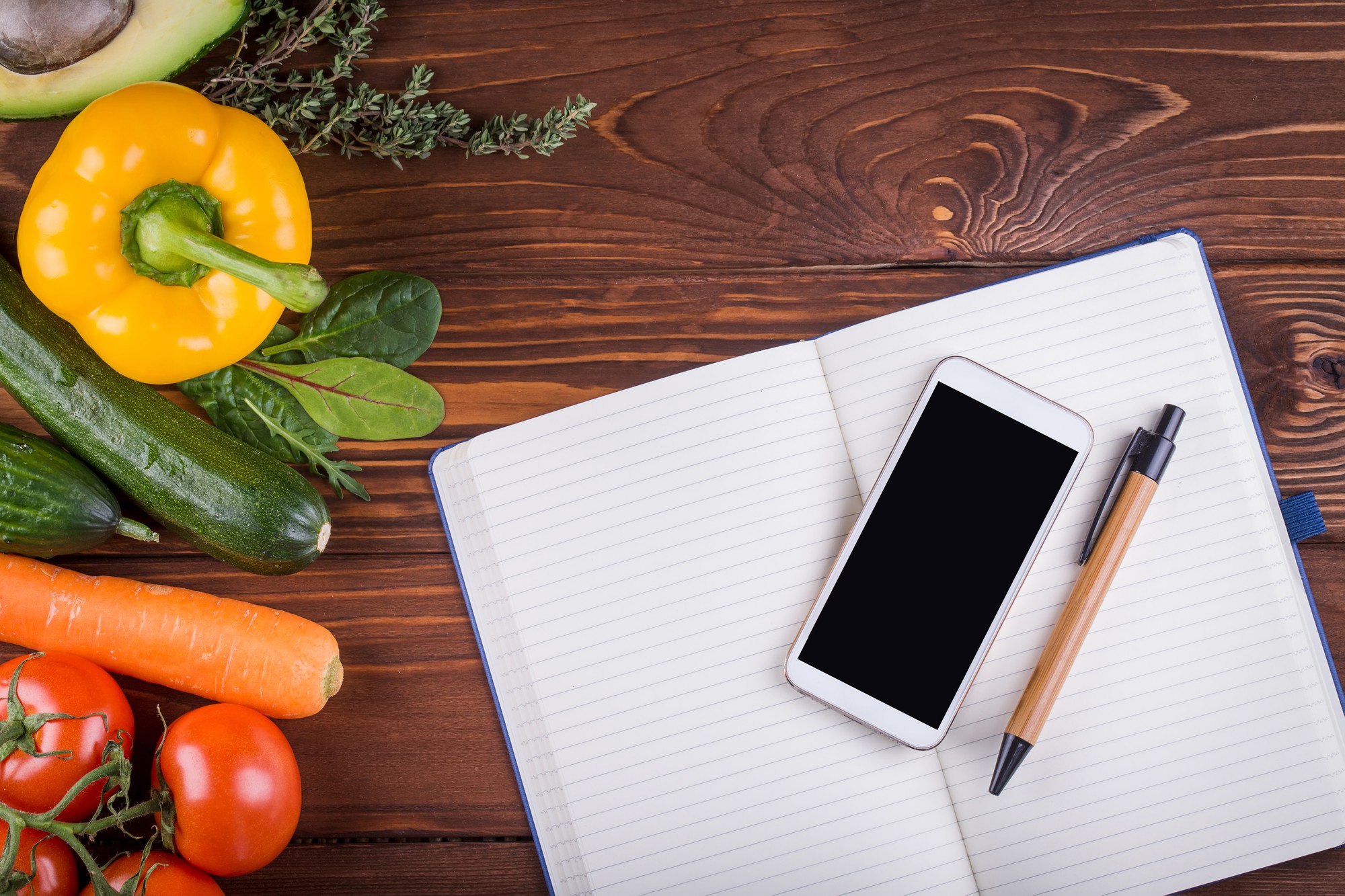 Flat lay of course materials: notebook, phone and herbs